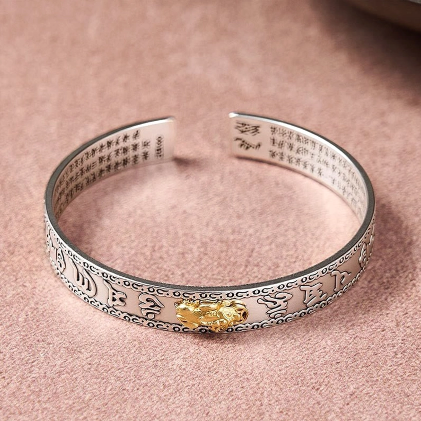 Open cuff Pixiu silver bangle bracelet with inner Heart Sutra inscriptions and gold Pixiu charm, flat lay top view