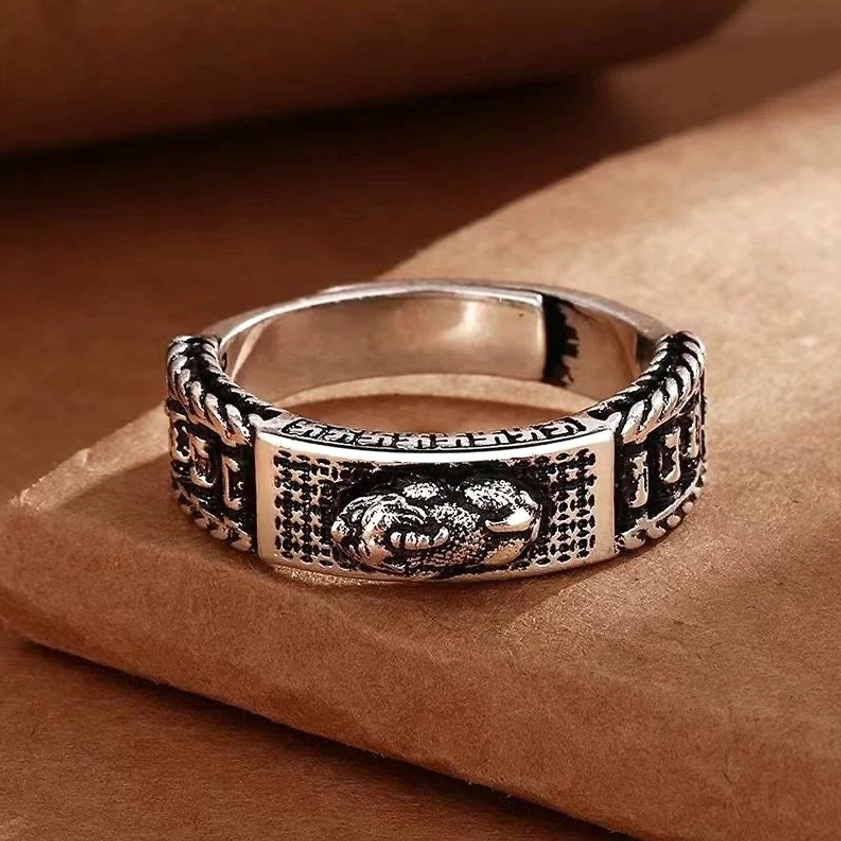 Pixiu wealth ring flat lay side view - central embossed Buddhist prosperity symbol with full carved retro patterns and braided silver ring sides