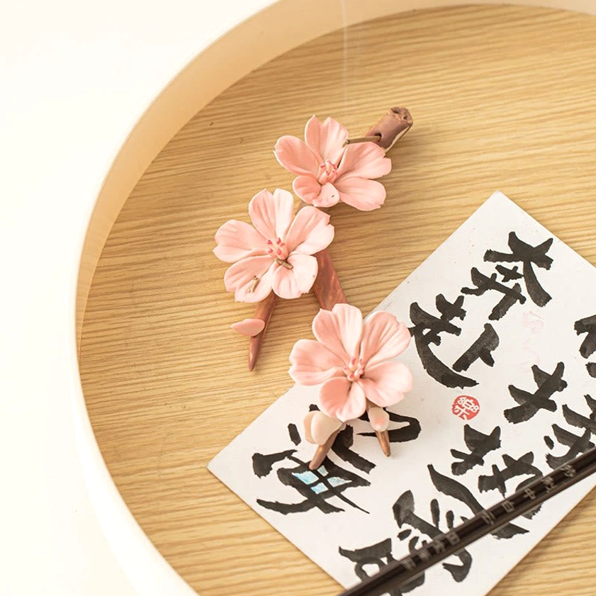 Detail view of ceramic plum blossom incense burner showing intricate pink floral details and branch texture