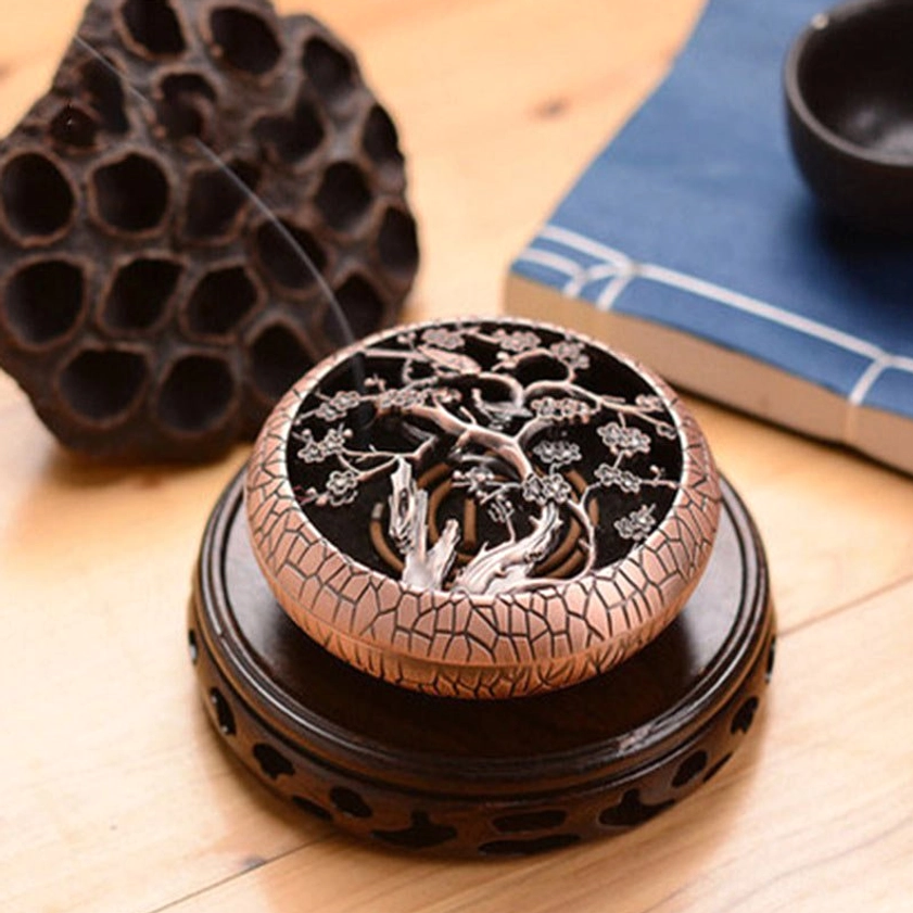 Plum flower pattern brass incense holder with burning coil incense, placed on wooden stand with lotus decoration, copper red textured finish showing authentic crackle detail