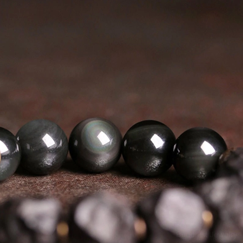 High-gloss polished black obsidian beads - close-up macro view showing reflective cat-eye sheen and natural stone quality