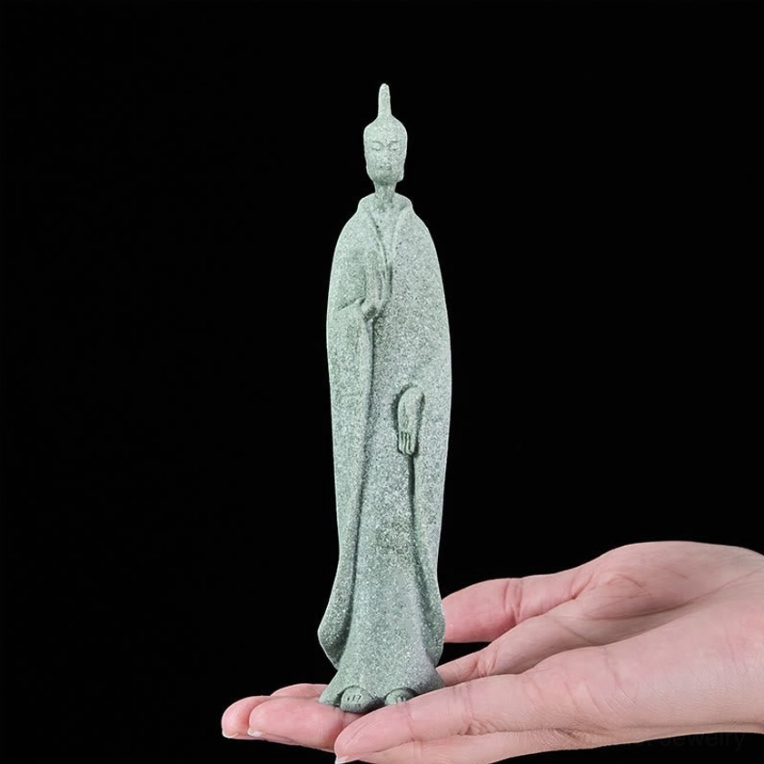Small standing Buddha statue held in palm of hand showing compact size and portability for meditation