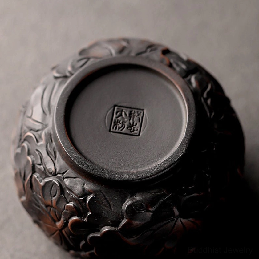 Bottom close-up of handcrafted ceramic tea cup showing official seal mark and full floral embossed exterior