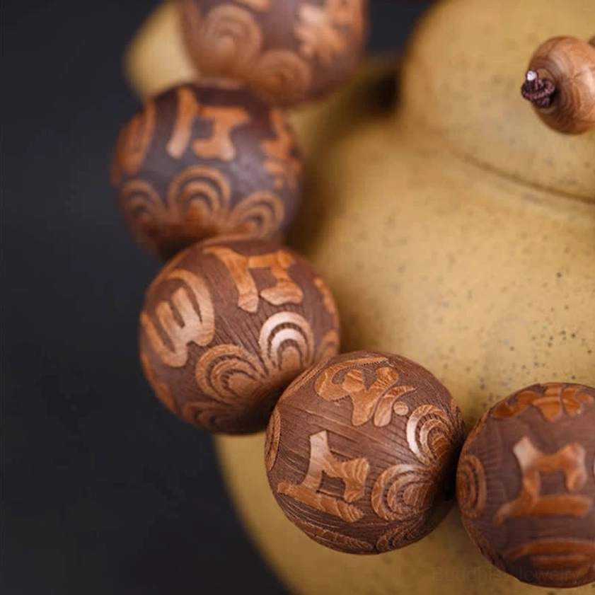 Close-up macro detail of engraved six-word mantra on Abelia Biflora wood beads showing natural texture