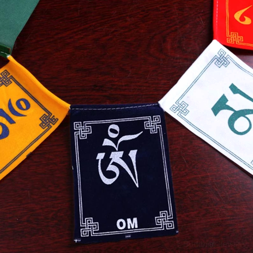 Handcrafted Buddhist prayer flags flat lay showing individual flags with sacred mantra script on wooden surface