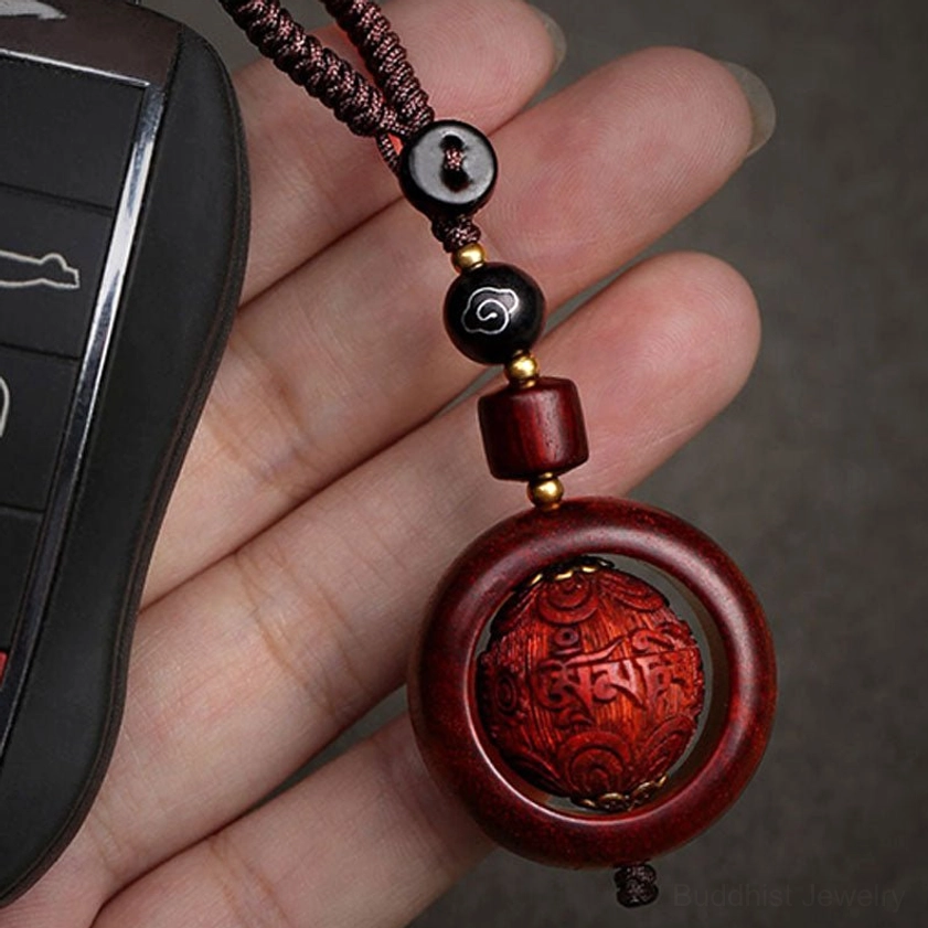 Red sandalwood prayer keychain displayed next to car key showing compact size and portable spiritual accessory use