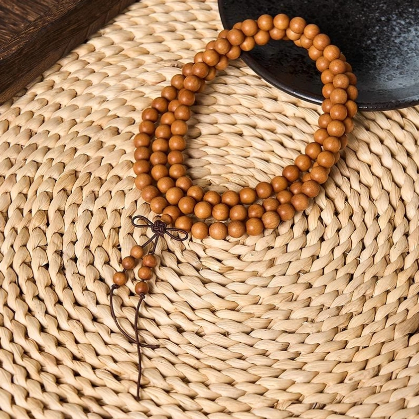 8mm red sandalwood meditation mala beads with dark brown knotted tassel on natural straw background