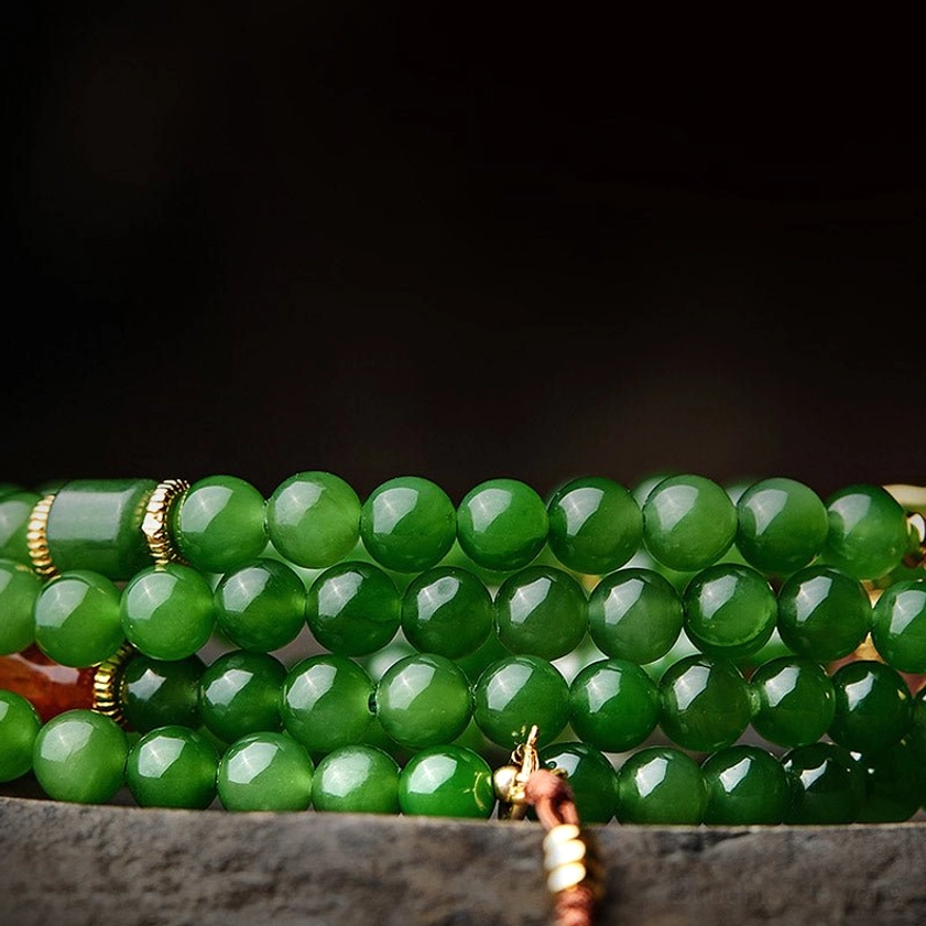 Detailed overhead view of dense jade prayer beads with metal connectors and hanging tassel