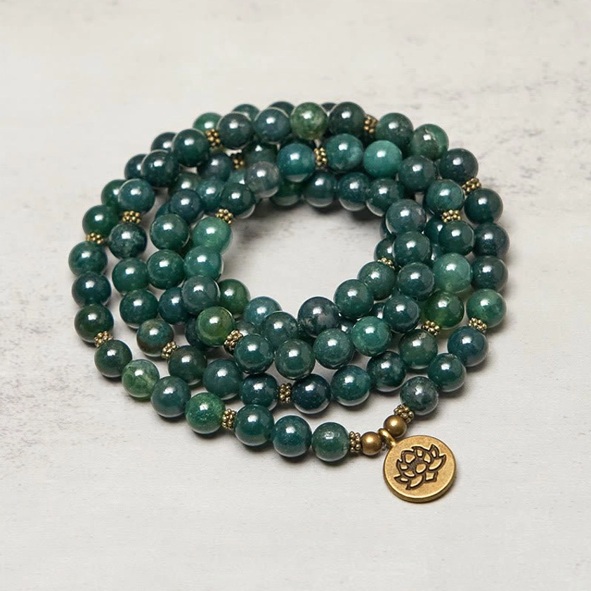 Coiled moss agate prayer beads mala overhead view showing gold tone lotus charm and round green agate beads for meditation practice