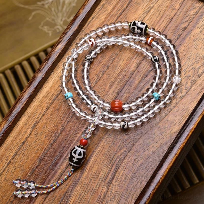 Multi-loop crystal glass mala with protective dzi pendant and colorful tassel on wooden tray