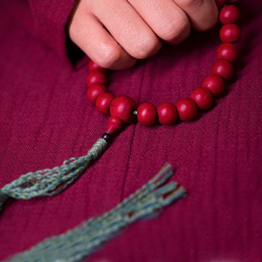 Buddhist wrist mala with long frayed teal tassel overhead view with hand and sleeve detail