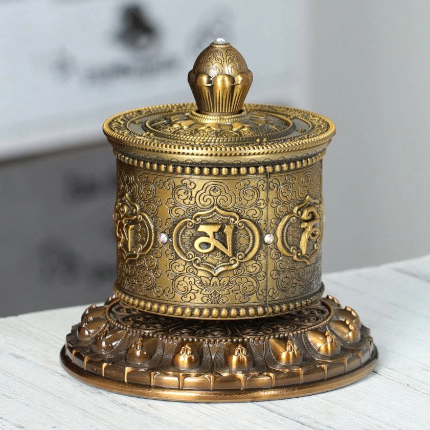 Front eye-level view of handcrafted Buddhist prayer wheel with classic embossed religious designs and Om Mani Padme Hum