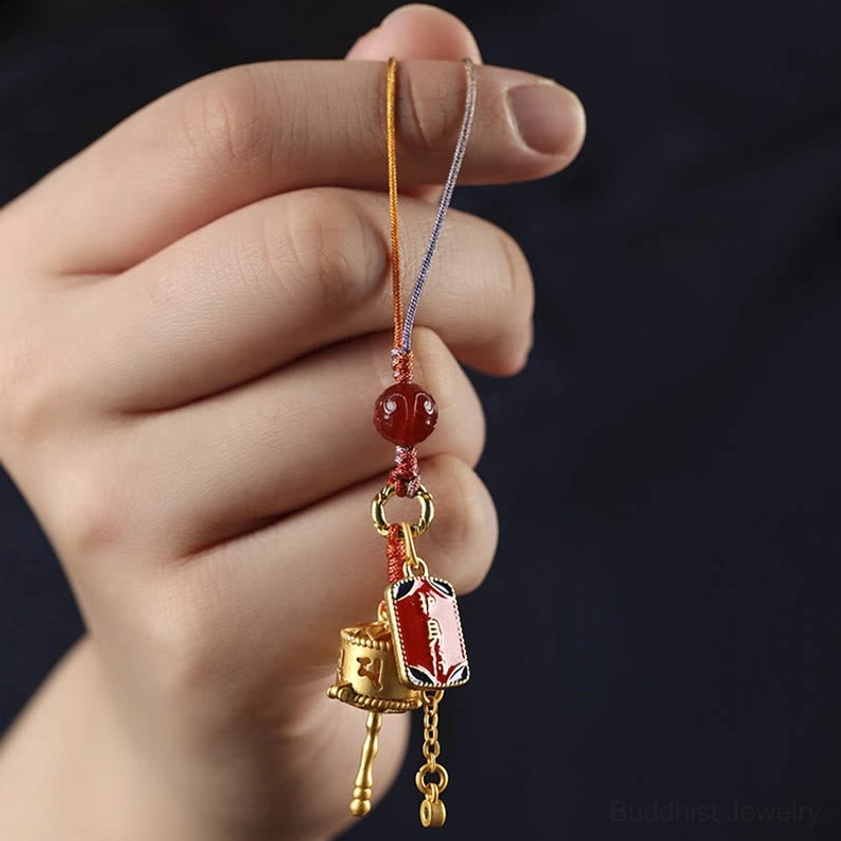 Prayer wheel charm components breakdown showing prayer wheel, enamel tags, connection ring, red agate bead and cord