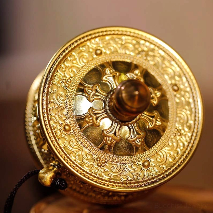 Close-up of Buddhist prayer wheel end cap, intricate gilt floral carvings with central wooden knob, showing fine handcrafted detail and traditional Buddhist iconography