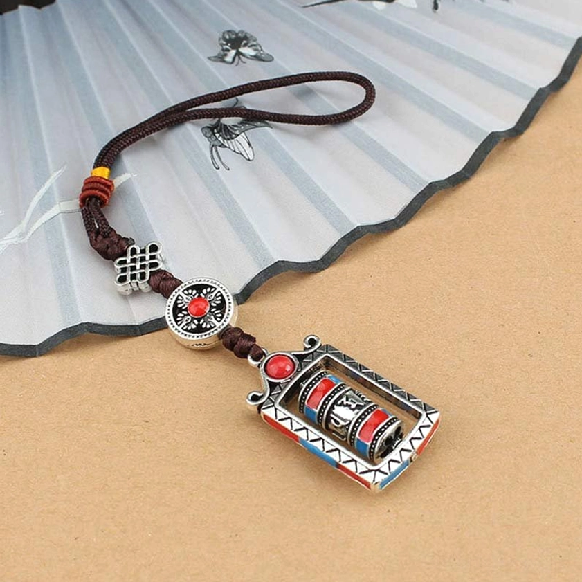 Prayer wheel hanging decoration with rotatable cylinder and brown braided cord on vintage background