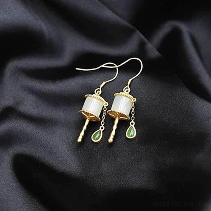 Buddhist jade prayer wheel drop earrings top-down flat lay on black silk fabric background, hook-type dangle with gold silver jade