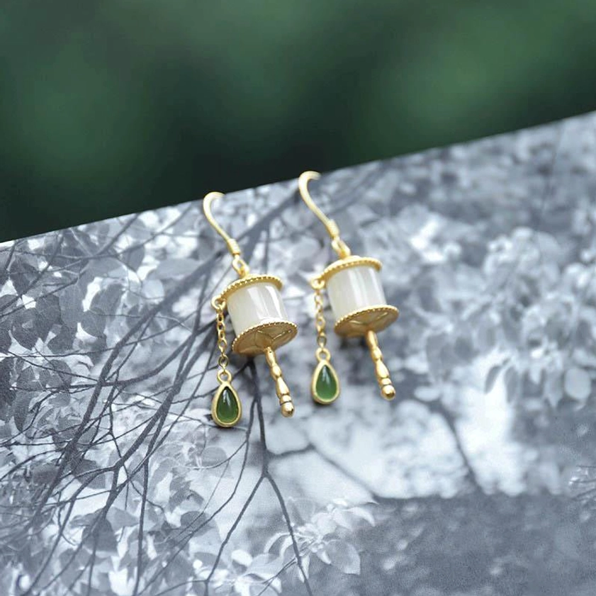 Jade prayer wheel drop earrings flat lay top-down view on black and white patterned surface, minimalist paired earrings design