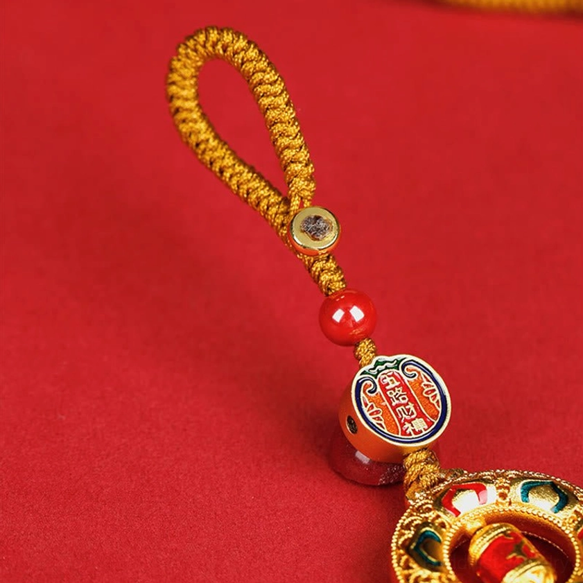 Close-up of rotatable copper prayer wheel keychain with inscribed metal tag and enamel embellishments