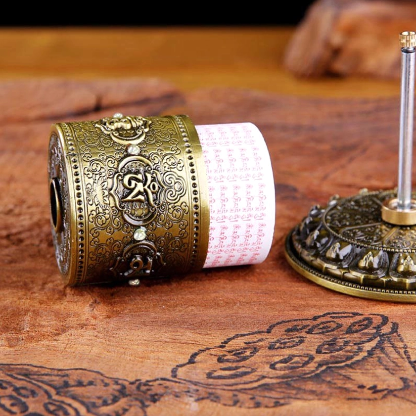 Overhead view of Buddhist prayer wheel ornament showing detailed lotus base and embossed cylinder with sacred patterns