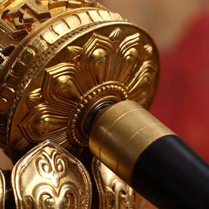 Close-up macro view of prayer wheel head showing gilt bronze lotus carvings and intricate Om Mani Padme Hum engraving