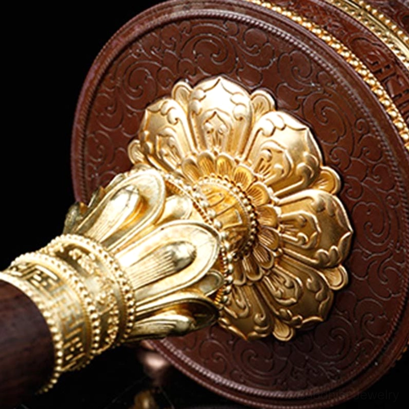 Rear view of Buddhist prayer wheel showing large gilded lotus flower ornament and embossed scroll base