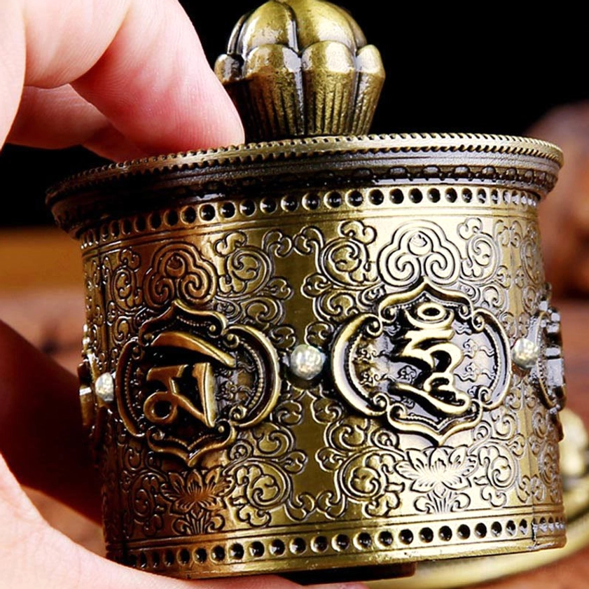 Side detail view of Buddhist prayer wheel showing relief carvings and rhinestone decorations on antique bronze finish