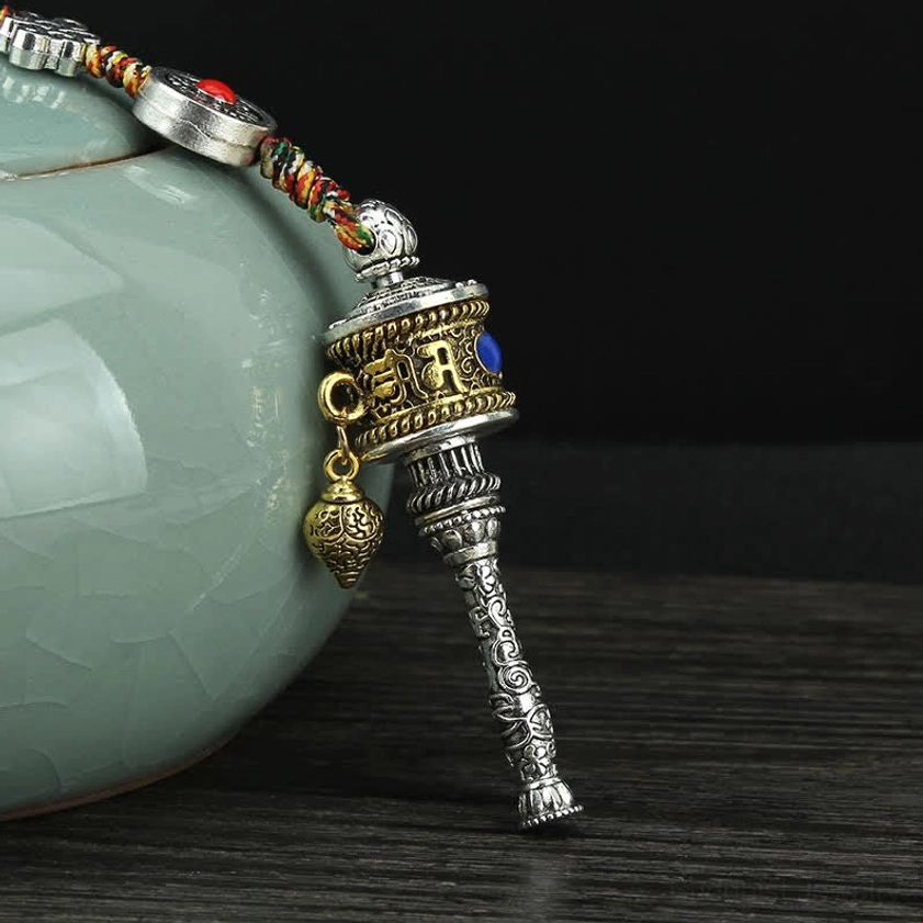 Single Buddhist prayer wheel hanging ornament with silver base, blue inlaid gemstone, engraved six-word mantra, and golden charm pendant