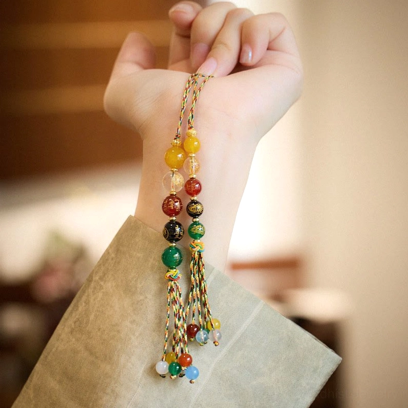 Tibetan Five Gods of Wealth agate charm worn on wrist showing multicolored agate beads and braided cord