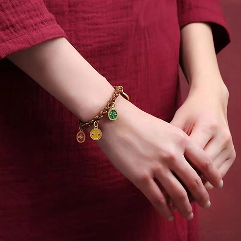 Five wealth deity bracelet wrapped around wrist showing thin braided rope and small metal pendants