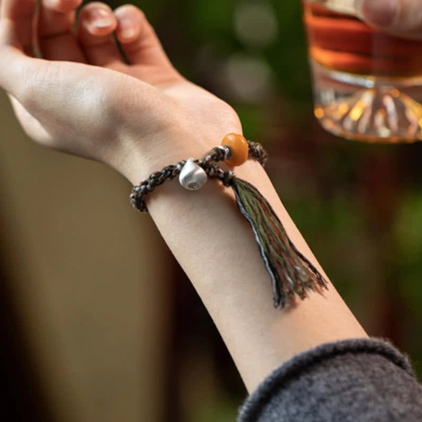 Daily wear Buddhist bracelet on wrist with slim braided cord and amber decorative bead