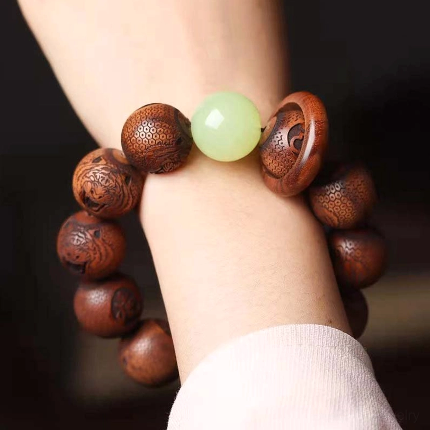 Close-up wrist shot of tiger engraved rosewood bracelet with carved script beads, jade bead, and wooden ring detail