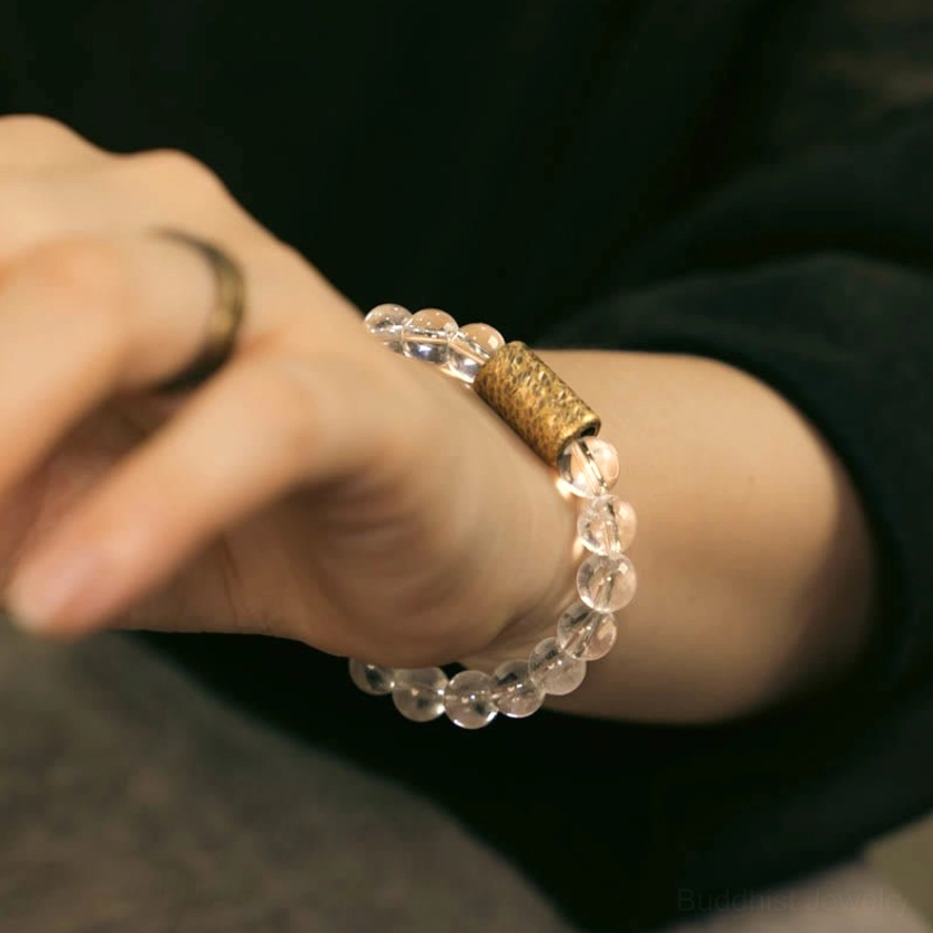 Clear quartz crystal bracelet worn on wrist with gold ring paired together on dark clothing