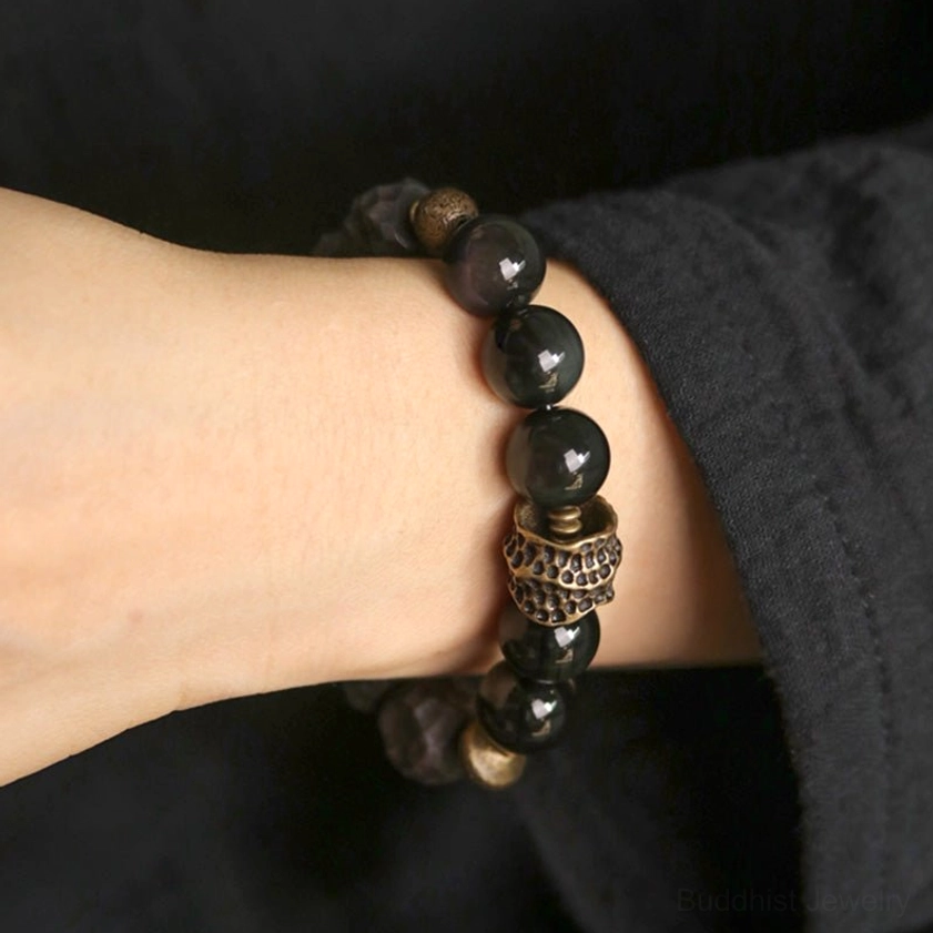 Buddhist protective couple bracelet close-up on wrist showing bronze decorative metal bead and natural stone beads