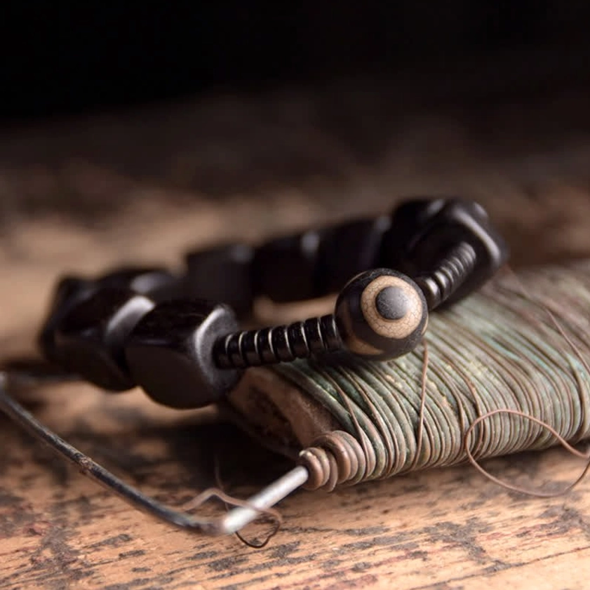 Ebony wood dzi bead bracelet showing protective amulet design with polished dark square beads and black spacers