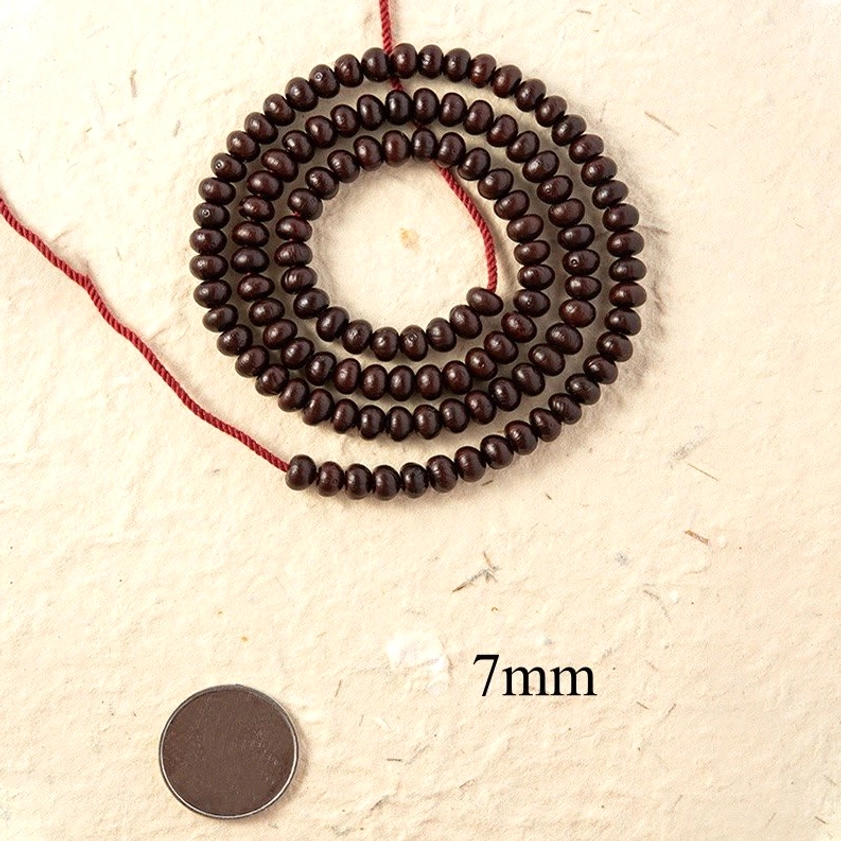 7mm purple bodhi seed mala bracelet flat lay with coin for size reference on beige paper