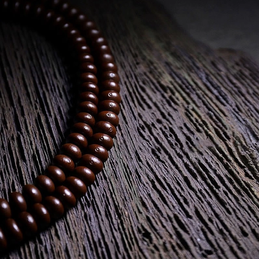 Matte purple bodhi seed beads in close-up flat lay showing natural lustre and texture