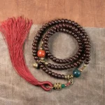 108 Purple Bodhi Seed Mala Bracelet top view flat lay on wooden surface with red tassel and mixed stone accents