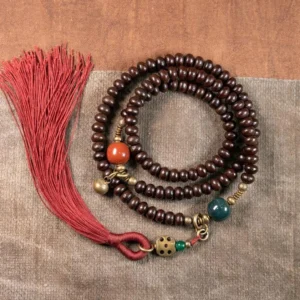 108 Purple Bodhi Seed Mala Bracelet top view flat lay on wooden surface with red tassel and mixed stone accents