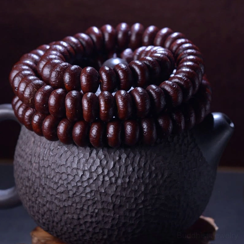 Purple Bodhi Seed 108 mala coiled neatly on dark textured teapot surface