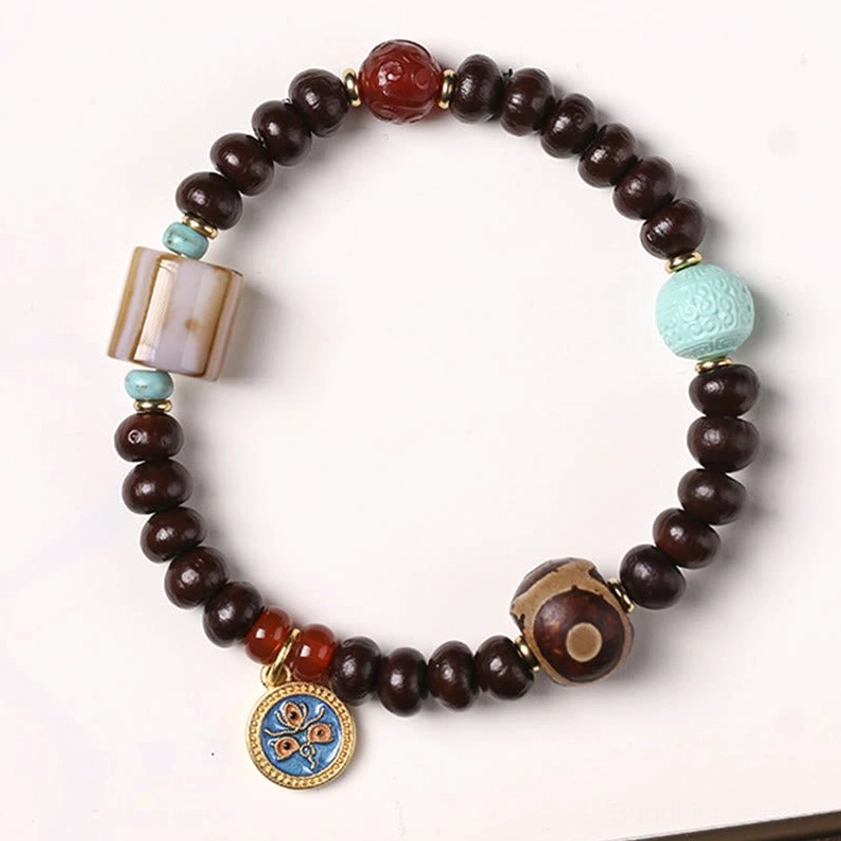 Close-up of authentic purple bodhi seeds with three-eye dzi bead and carved agate on neutral background