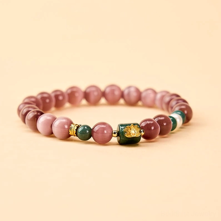 Front flat lay view of purple cat's eye lotus bracelet with central gold lotus charm and coordinated beads on light beige background