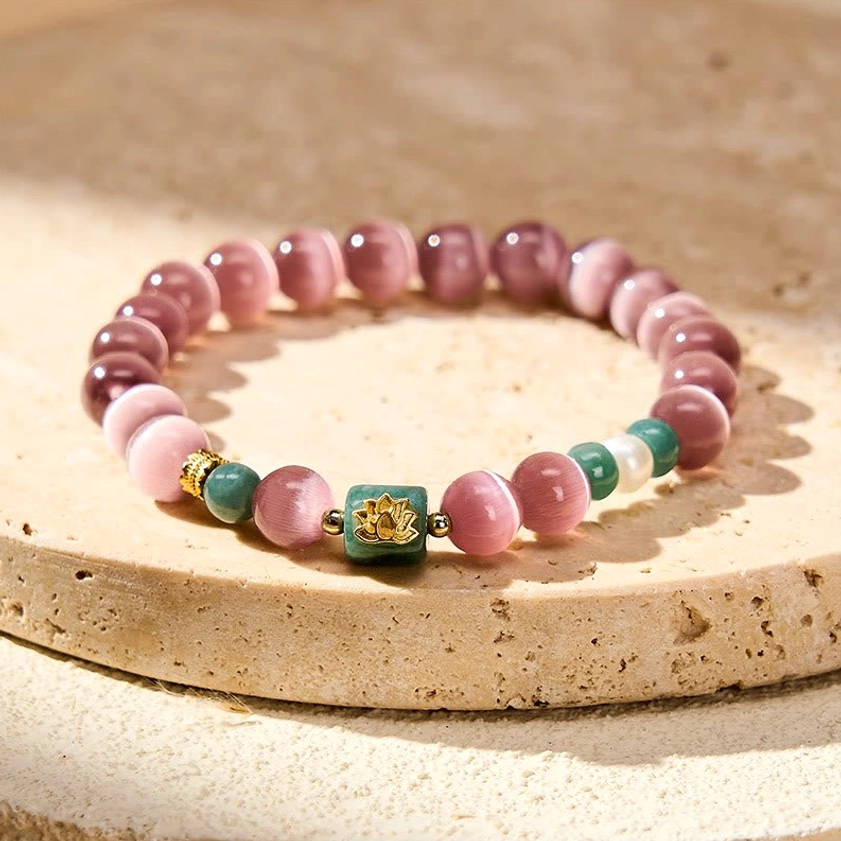 Purple cat's eye lotus beaded bracelet with gold lotus charm and matching accent beads displayed on wooden coaster, top-down flat lay view