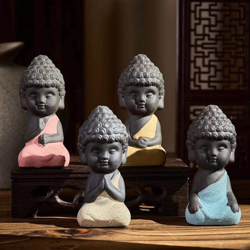 Four handcrafted purple clay Buddha statues with colorful robes on wooden surface, meditation and mindfulness desk decorations