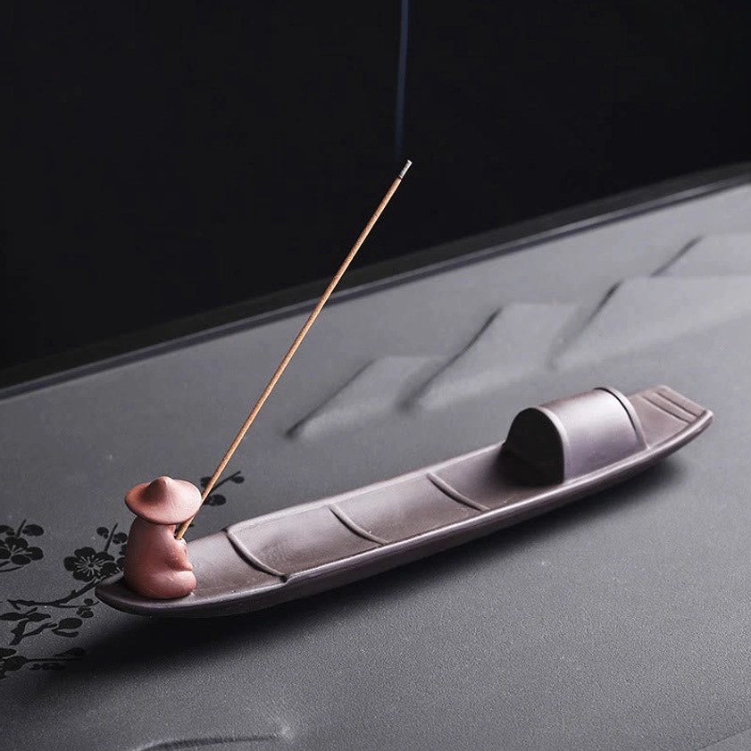 Purple clay Buddhist incense burner with fisher figurine, left side profile showcasing rising aromatic smoke and traditional incense holder craftsmanship