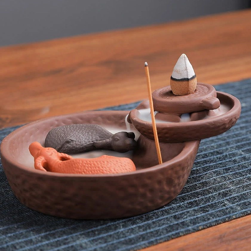 Buddhist ceramic incense holder with hammered purple clay surface, ox decorations and incense stick placement, right oblique view