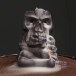 Purple clay skull backflow incense burner front view with flowing smoke and stick incense