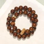 Purple Gold Rat Bodhi Seed double wrap bracelet flat lay top view with reddish-brown glossy beads and decorative metal accents