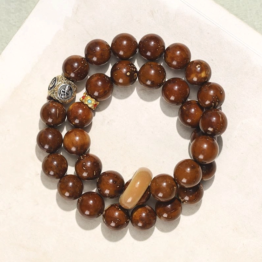 Purple Gold Rat Bodhi Seed double wrap bracelet flat lay top view with reddish-brown glossy beads and decorative metal accents