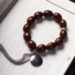 Purple gold rat bodhi bracelet with OM charm flat lay on calligraphy paper - wealth prosperity bracelet