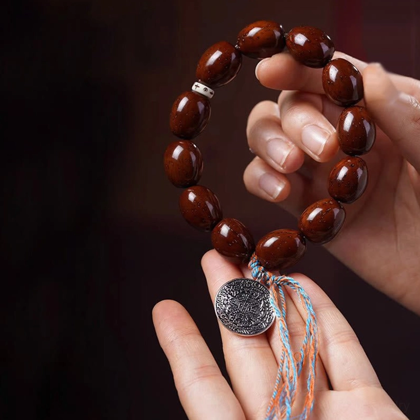 Close-up hand-held purple gold rat bodhi bracelet with silver OM medallion and Chinese zodiac charm